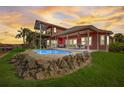 Two-story waterfront home with private pool and patio at sunset at 300 Quay Assisi Ct, New Smyrna Beach, FL 32169