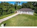 Single-story house with driveway, green lawn, and wooded surroundings at 1004 W 7Th St, New Smyrna Beach, FL 32168