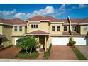 Two-story townhome with red tile roof, two-car garage, and brick driveway at 3608 Romea Cir, New Smyrna Beach, FL 32168