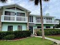 Two-story light teal house with balconies, stone accents, and a landscaped yard at 1012 S Riverside Dr, Edgewater, FL 32132