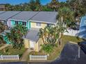 Brightly colored two-story townhome with a white picket fence and tropical landscaping at 4017 Saxon Dr, New Smyrna Beach, FL 32169