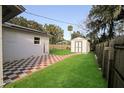 Checkered-tile patio, storage shed, and grassy backyard with wooden fence at 437 Perdita Ave, Edgewater, FL 32132