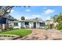Quaint mid-century home with lush landscaping and a brick driveway at 624 S Pine St, New Smyrna Beach, FL 32169