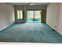 Spacious living room with teal carpet and sliding glass doors at 200 S Riverside Dr # 2010, New Smyrna Beach, FL 32168