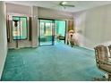 Living room with teal carpet, sliding doors, and balcony access at 200 S Riverside Dr # 2010, New Smyrna Beach, FL 32168