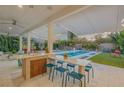 Outdoor kitchen, pool, and lounge area with modern furniture and retractable awnings at 2022 N Peninsula Ave, New Smyrna Beach, FL 32169