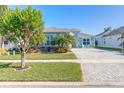 Landscaped front yard with lush greenery and a paver driveway at 265 Venetian Palms Blvd, New Smyrna Beach, FL 32168