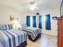 Bedroom with two twin beds, tile floor, and ceiling fan at 5300 S Atlantic Ave # 1-203, New Smyrna Beach, FL 32169