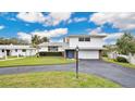 Single-Gathering home with a welcoming front yard, mature trees, and paved driveway at 1916 S Peninsula Dr, Daytona Beach, FL 32118