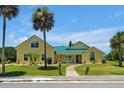 Beautiful yellow house with green metal roof, palm trees, and walkway at 886 Matthews Ave, New Smyrna Beach, FL 32169