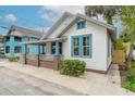 Quaint cottage with a white exterior, blue accents, and a wooden fence at 208 Douglas St, New Smyrna Beach, FL 32168