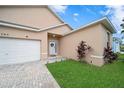 Front view of a tan house with a white garage door and landscaping at 165 Captain Hook Way, Davenport, FL 33837