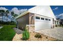 Attached garage with stone accents and landscaping at 6437 Sw 180Th Cir, Dunnellon, FL 34432
