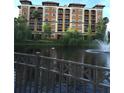 Resort-style building exterior overlooking a tranquil lake with fountain at 12521 Floridays Resort Dr # 302F, Orlando, FL 32821