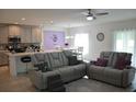 Open-concept living room, kitchen, and dining area with gray sectional sofa at 964 Avenal Ln, Davenport, FL 33837