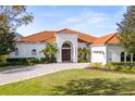 Front view of Mediterranean-style home with tile roof and lush landscaping at 7487 Gathering Dr, Reunion, FL 34747