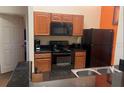 Kitchen with wood cabinets, black appliances, and granite countertops at 8100 Poinciana Blvd # 2203, Orlando, FL 32821