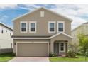 Two-story house with tan siding and a two car garage at 1458 Woodmont Blvd, Kissimmee, FL 34746