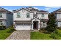 Two-story house with a white exterior, gray stone accents, and a three-car garage at 8911 Stinger Dr, Champions Gate, FL 33896