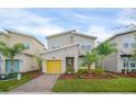 Modern two-story home with a yellow garage door and landscaped front yard at 751 Drop Shot Dr, Davenport, FL 33896