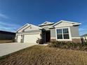 Gray three-car garage home with a well-manicured lawn at 14415 Travois Way, Winter Garden, FL 34787