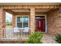 Front porch with stone columns, red door, and seating area at 5039 Ne 125Th Loop, Oxford, FL 34484