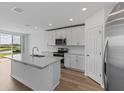 Kitchen features white cabinets, stainless steel appliances, and a large island overlooking the backyard at 3606 Walking Stick Way, Poinciana, FL 34759