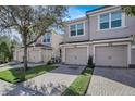Three-unit townhome building with attached garages and manicured lawn at 8316 Fontera Dr, Davenport, FL 33896