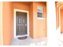 Dark brown front door with a decorative mat and white columns at 868 Assembly Ct, Reunion, FL 34747