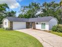 White house with a stone facade, a two-car garage, and a well-maintained lawn at 3130 Willow Oak Dr, Edgewater, FL 32141