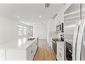 Open concept kitchen with white cabinets, island and wood-look floors at 1925 Harrods Pl, Haines City, FL 33844