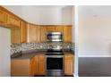 Kitchen with wood cabinets, stainless steel appliances, and mosaic backsplash at 221 Rosa Ave, Oviedo, FL 32765