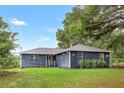 Newly remodeled home featuring a dark blue exterior and a well-manicured lawn at 10 Locust Run Crse, Ocala, FL 34472