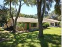 Rear view of a tan house with a covered patio and lush lawn at 32525 Oak Park Dr, Leesburg, FL 34748