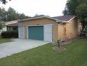 Tan house with a two-car garage and nicely landscaped front yard at 32525 Oak Park Dr, Leesburg, FL 34748