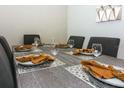 Close-up view of a modern dining table set for six with elegant place settings at 4731 Clock Tower Dr # 101, Kissimmee, FL 34746