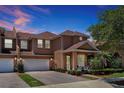 Two-story townhome with two-car garage and front porch at dusk at 3587 Casalta Cir, New Smyrna Beach, FL 32168