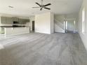 Open-concept living room with high ceilings, grey carpet, and kitchen views at 3696 Sagefield Dr, St Cloud, FL 34773