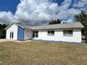 Ranch style home with white and blue exterior, showcasing a spacious yard at 7313 Cabor Ct, Orlando, FL 32818