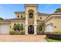 Two-story house with a tan facade, brown roof, and an arched entryway at 1160 Grand Traverse Pkwy, Reunion, FL 34747