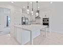 Modern white kitchen with island, stainless steel appliances, and glass pendant lights at 9832 Bucklow Hill Dr, Orlando, FL 32832