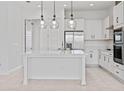 Modern white kitchen with island, stainless steel appliances, and glass pendant lights at 9832 Bucklow Hill Dr, Orlando, FL 32832