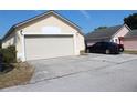 Tan house with a two-car garage and a dark-colored car parked in the driveway at 50989 Highway 27 Lot 317, Davenport, FL 33897