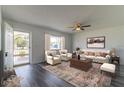 Living room with a gray floor, off-white couch, and ceiling fan at 17775 Se 101St Ct, Summerfield, FL 34491