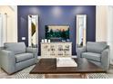 Living room featuring two armchairs, a coffee table, and a large TV at 2984 Salted Rim Rd, Kissimmee, FL 34747