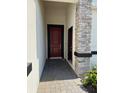 Covered entryway with a modern red door and stone pillar at 2927 Camden Way, Davenport, FL 33837