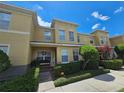 Two-story townhome with yellow exterior, featuring a porch and landscaping at 5434 River Rock Rd, Lakeland, FL 33809