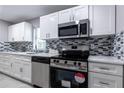 Renovated kitchen with white shaker cabinets, stainless steel appliances, and mosaic backsplash at 805 Lockhart St, Daytona Beach, FL 32114