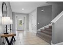 Bright entryway with tile flooring, staircase, and console table at 7481 Marker Ave, Kissimmee, FL 34747