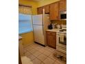 Condo kitchen with wood cabinets, white appliances, and tile floor at 6182 Willowpointe # B201, Orlando, FL 32822